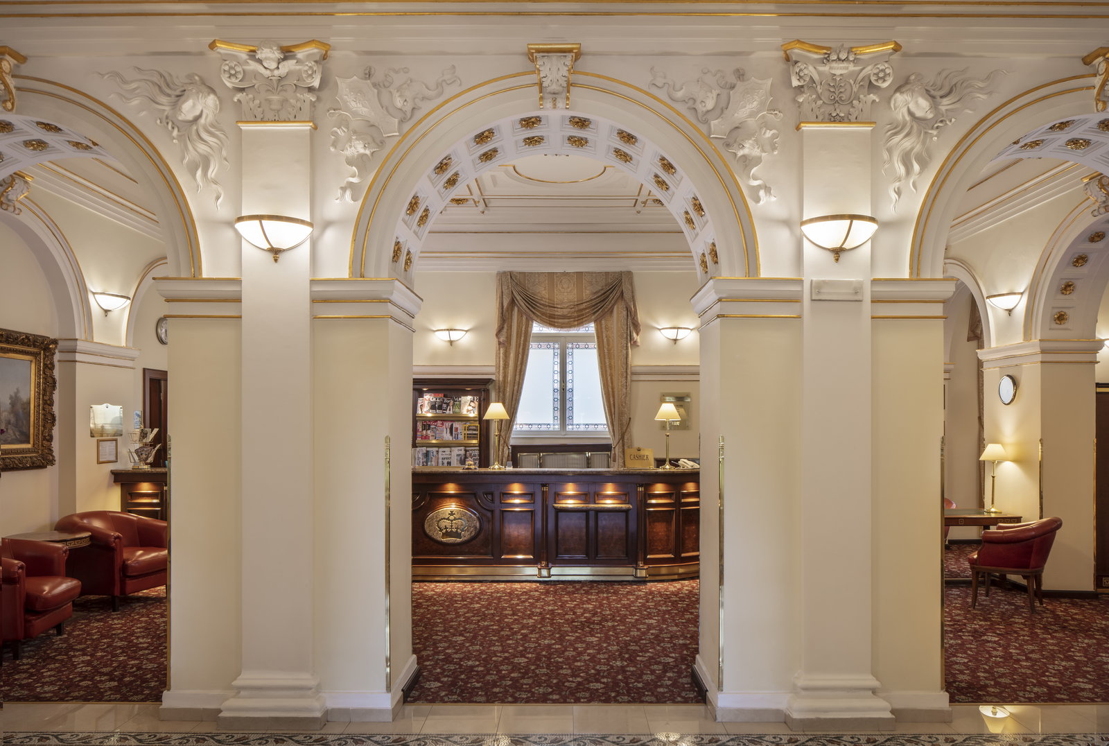 An ornate white-and-gold archway framing a hotel reception beyond