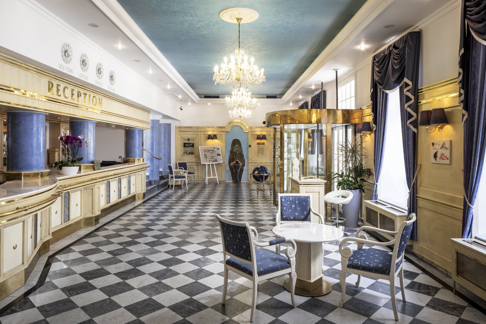 A hotel reception with a checkerboard marble floor and crystal chandelier