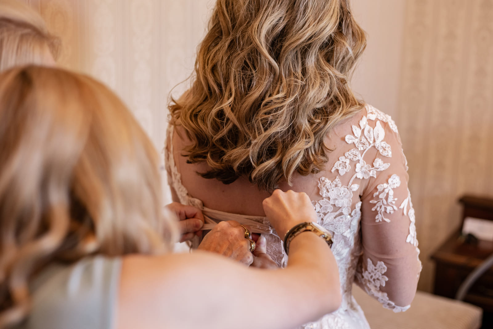 Die Braut beim Anlegen des Brautkleids