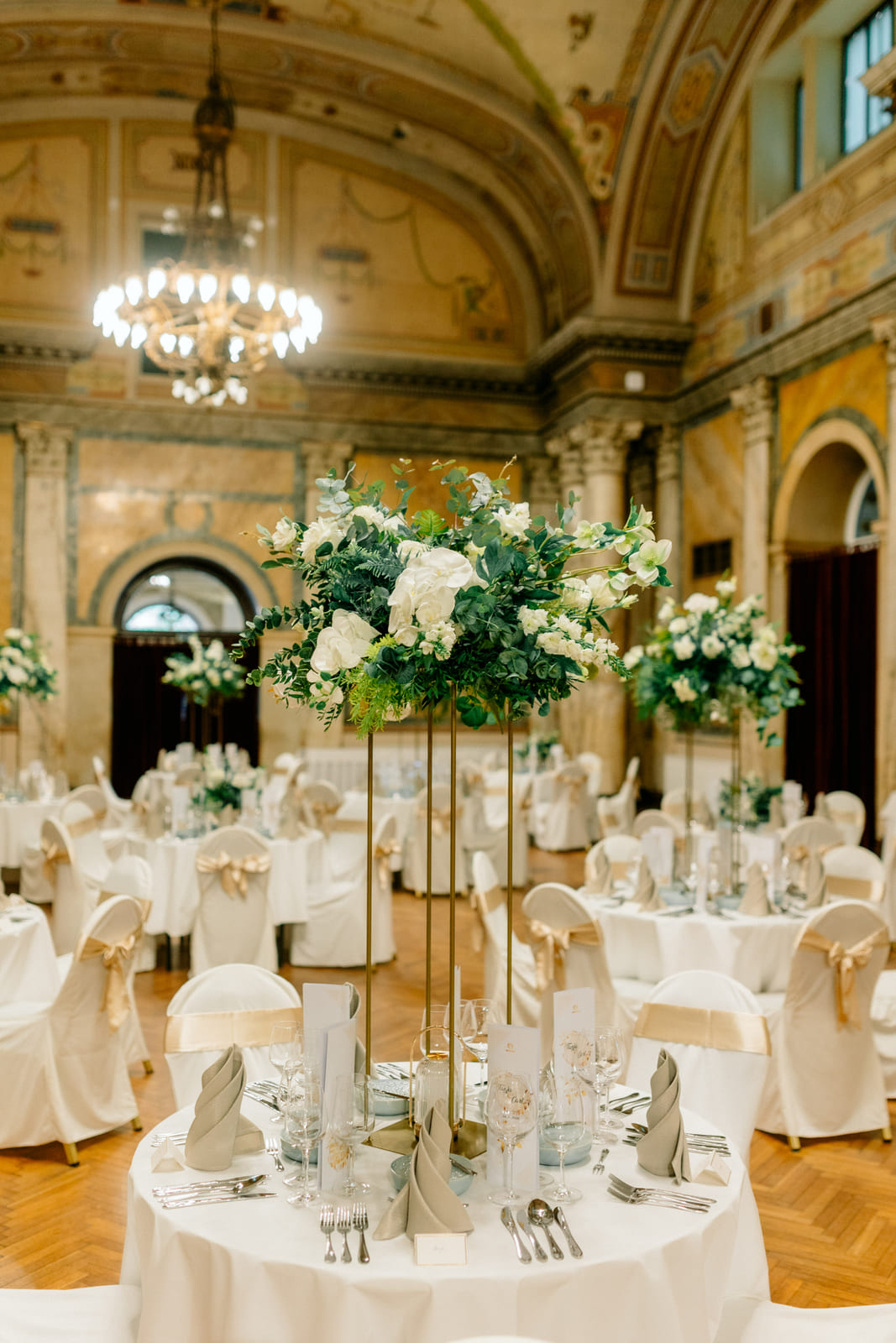 Hohe Blumendekoration auf der Hochzeitstafel im historischen Saal