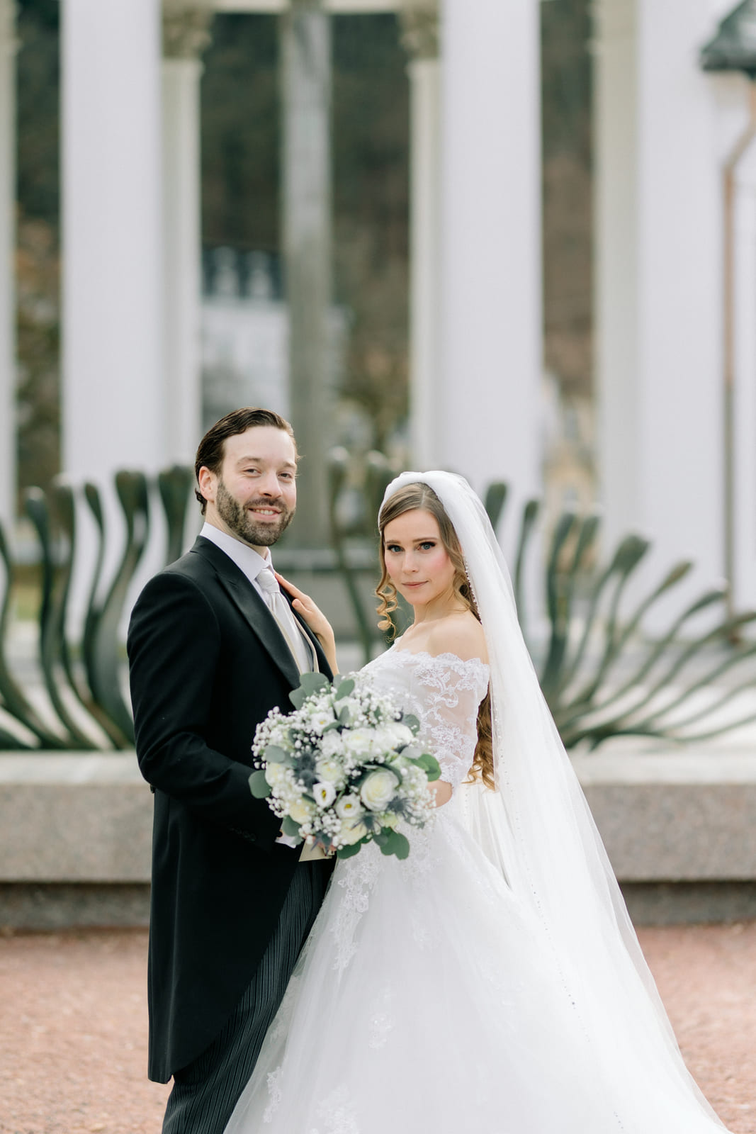 Hochzeitspaar mit Brautstrauß vor der Säulenreihe der Kolonnade