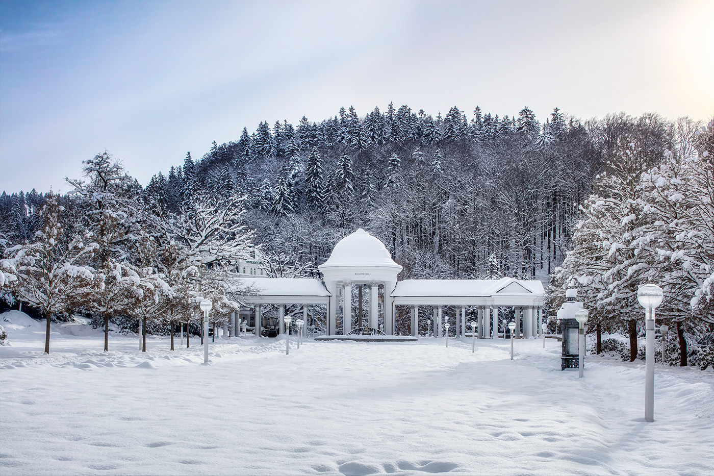 Domed colonnade of the Caroline and Rudolph springs in a snow-covered park below the forest